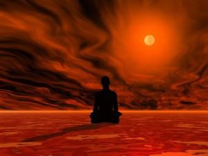 Man meditating on red ground in front of burning sun